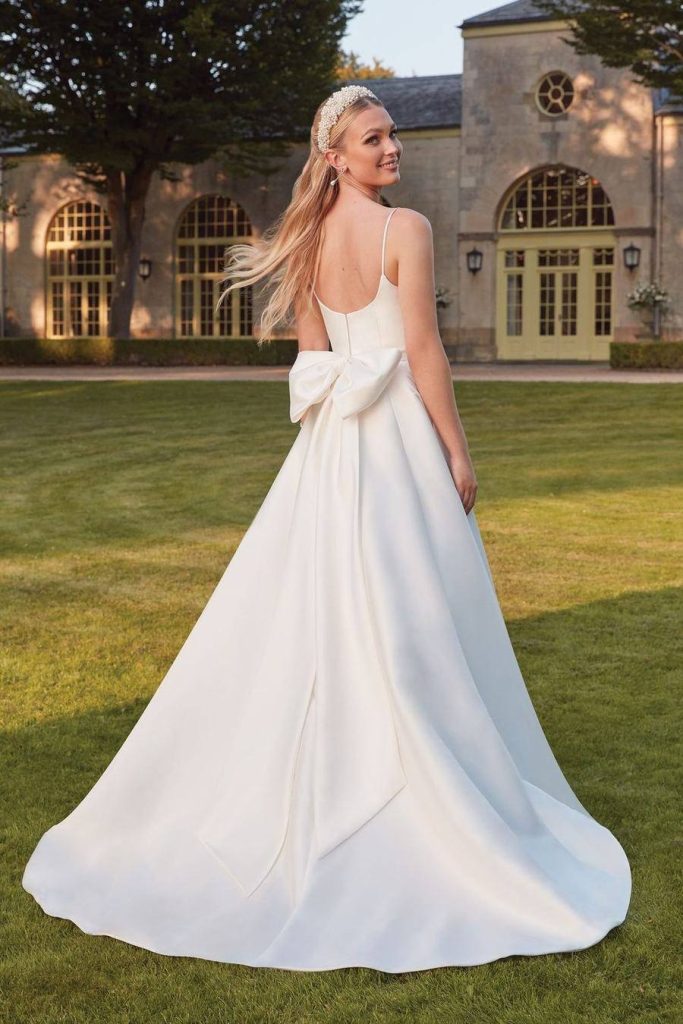 Spaghetti strap satin gown with an oversized bow at the back and a sweeping train