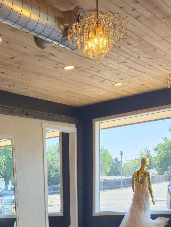 Crystal chandelier against the reclaimed plank ceiling, with a gown displayed in the front window
